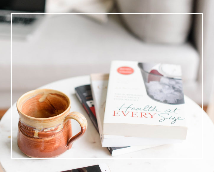 Coffe mug next to a stack of books | Shelby McDaniel